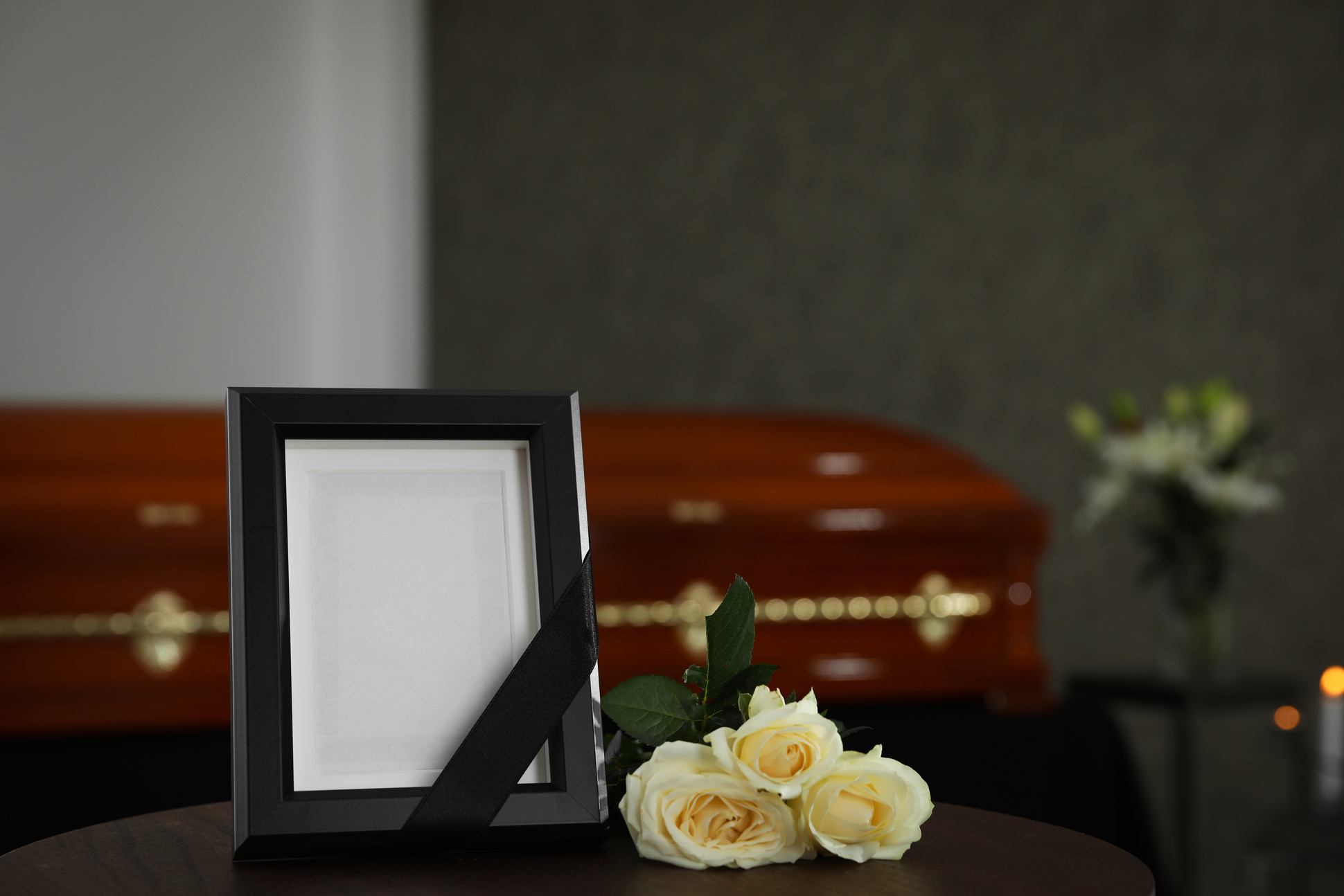 Black Photo Frame and White Roses on Table in Funeral Home